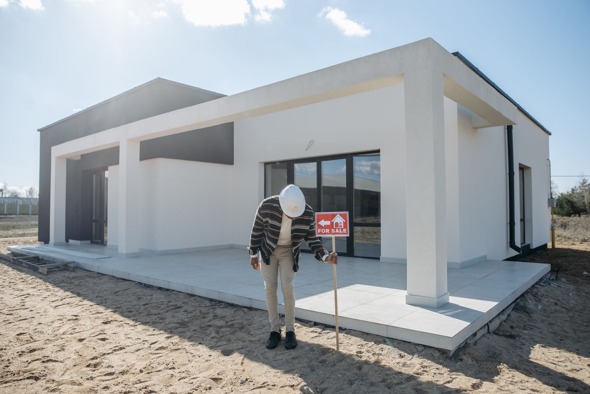 Agent immobilier casqué devant une maison à vendre