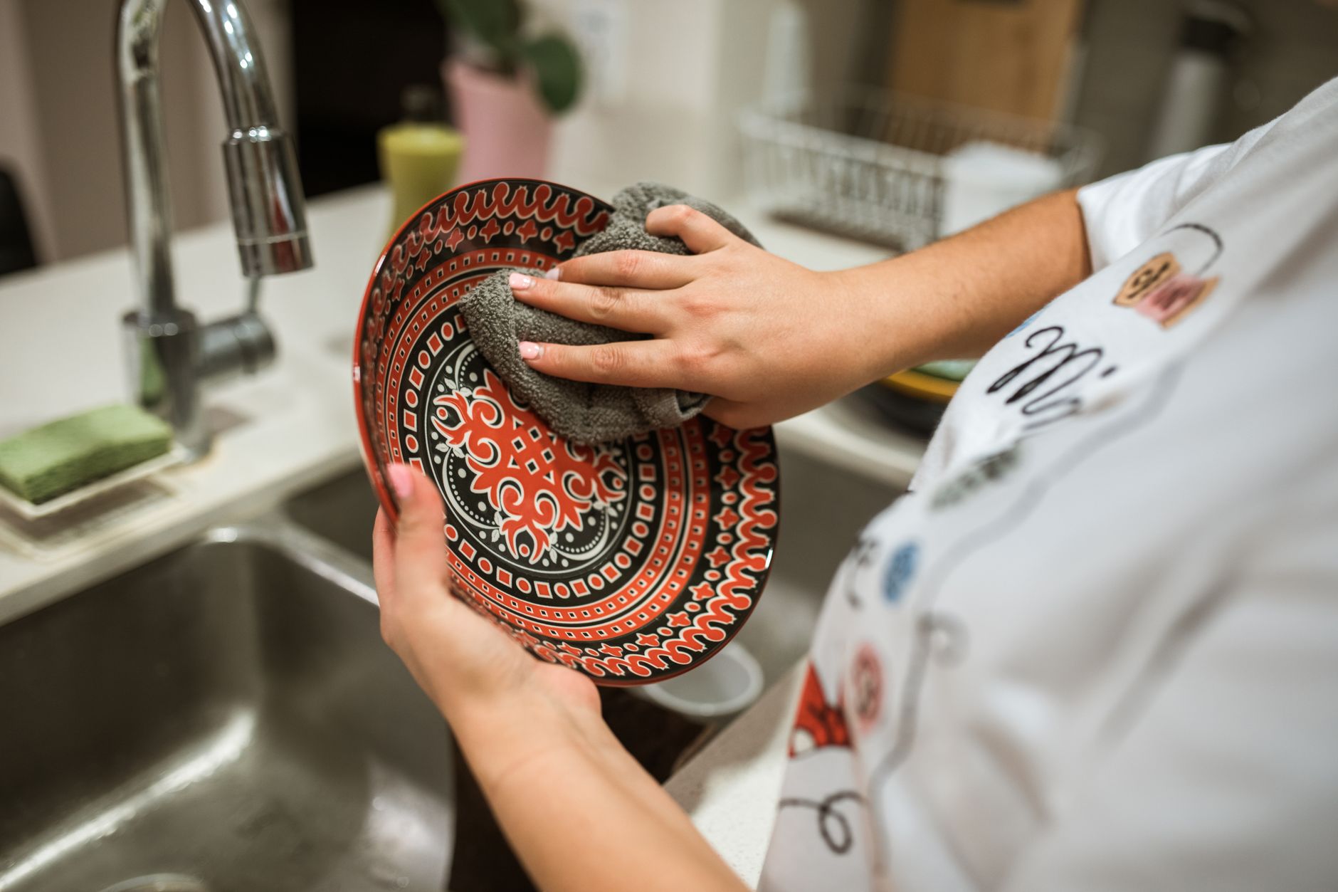 Rinçage d'une assiette colorée à la main dans la cuisine