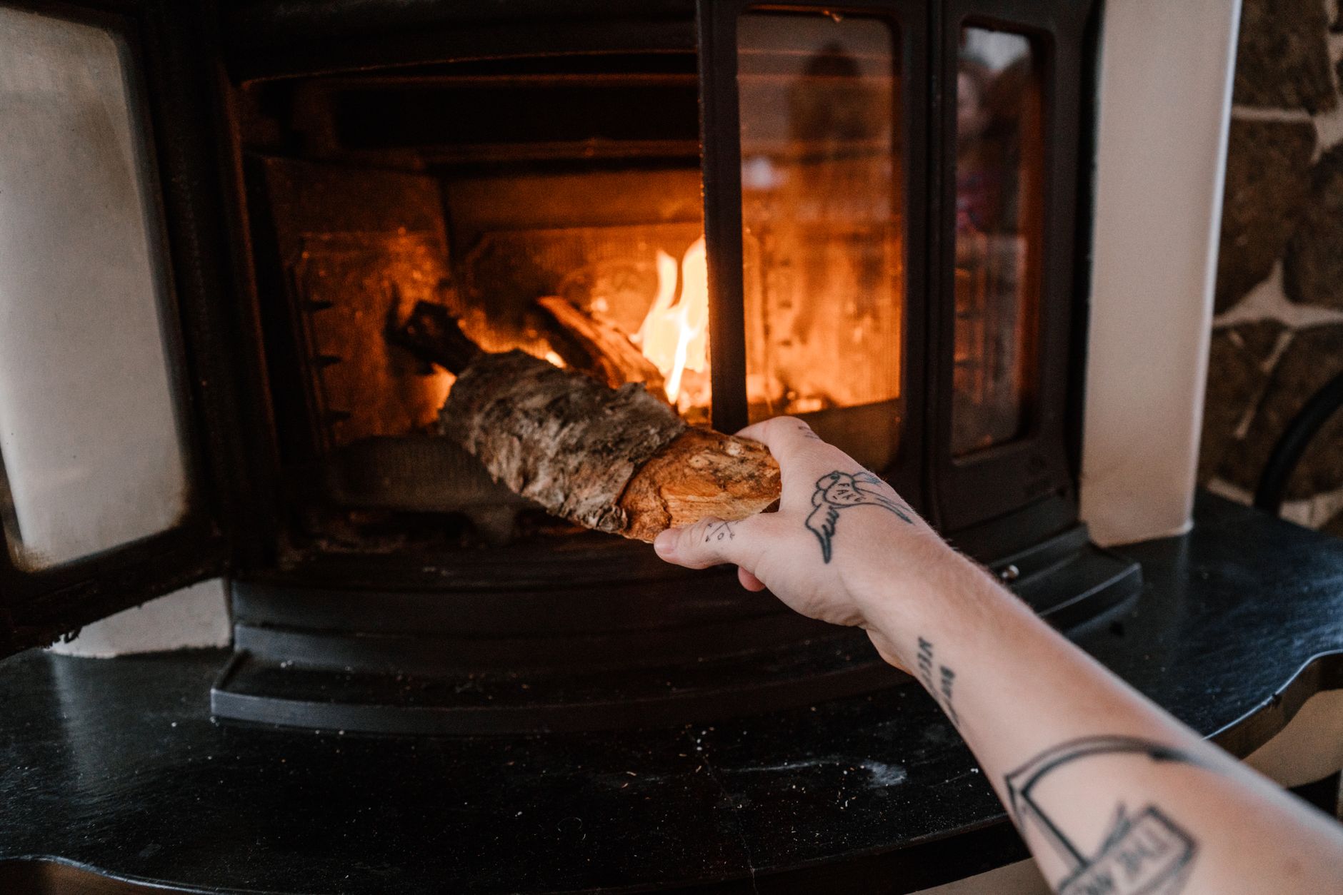 Main déposant une bûche dans un feu